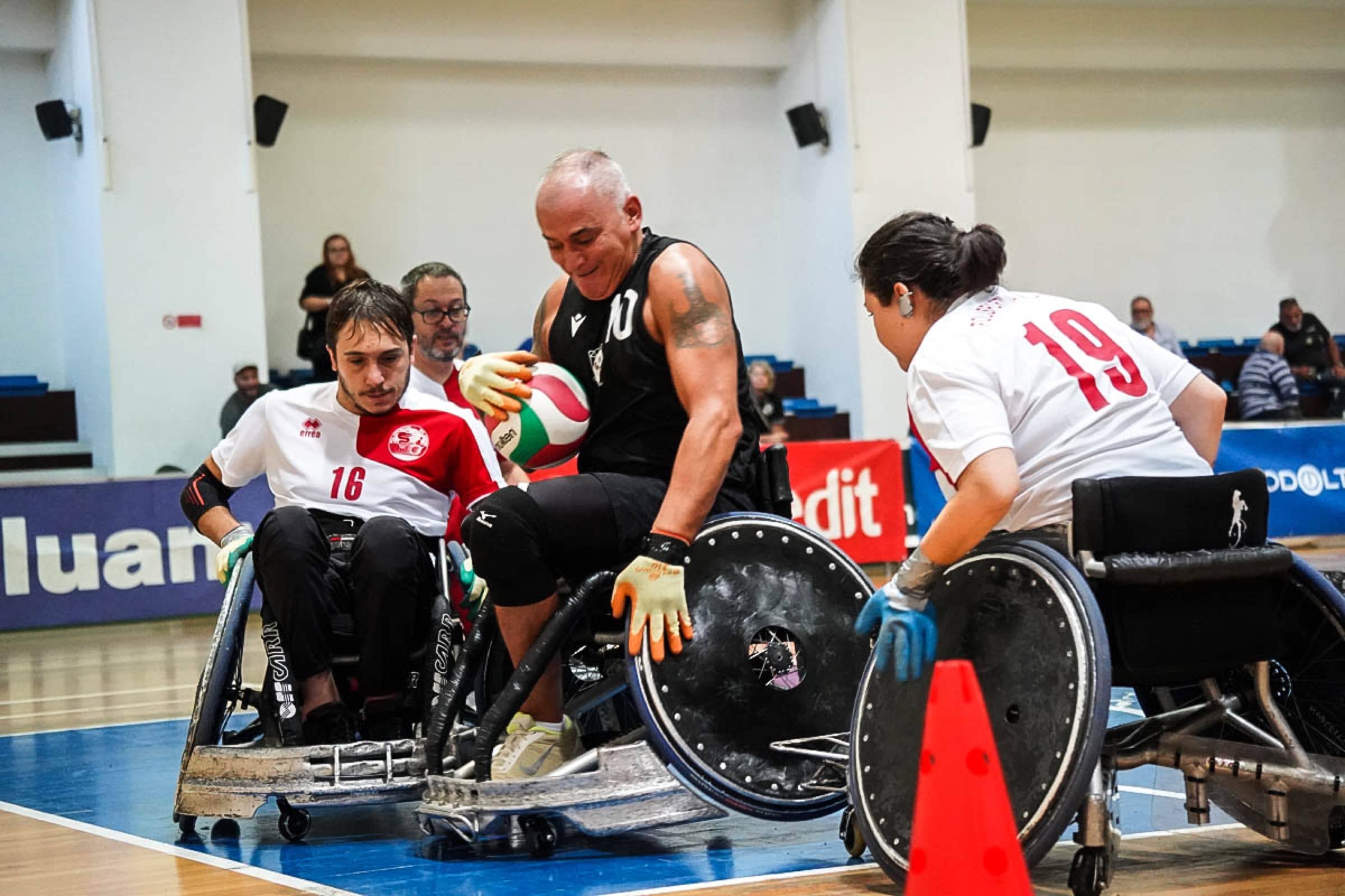 Un placcaggio di wheelchair rugby: tre atleti in carrozzina si scontrano per la palla durante una partita dei Romanes.